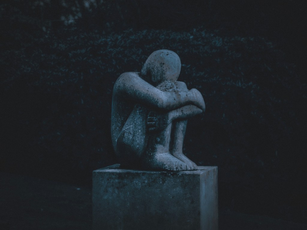 what is whump in fiction - imagine of a statue of a person huddled in quiet suffering